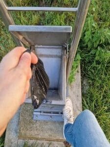 Op deze afbeelding zie je mij een zakje hondenpoep weggooien in een hondentoilet