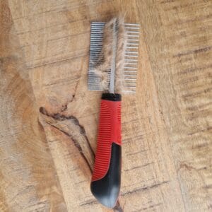 Metalen kam met losse vacht van Teddy na het borstelen